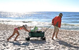 child helping pull wagon at beach