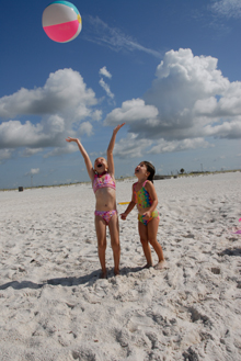 Little girls playing with beach ball on sand