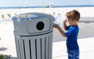 little boy throwing trash away at the beach
