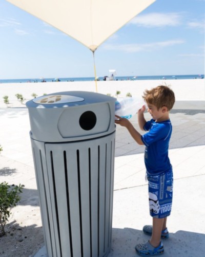 little boy throwing trash away at the beach