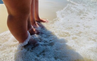 A person's feet in the water Description automatically generated with low confidence