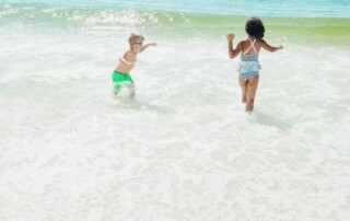 Two kids playing in the ocean Description automatically generated with low confidence